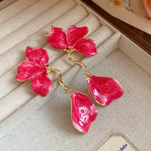 Close-up view of elegant pink enamel flower drop earrings in a velvet jewelry box.