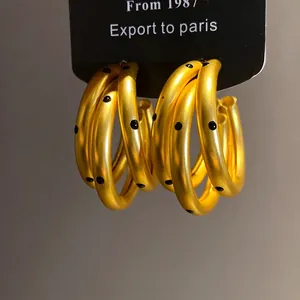 Elegant matte gold hoop earrings with black polka dots and sterling silver needles