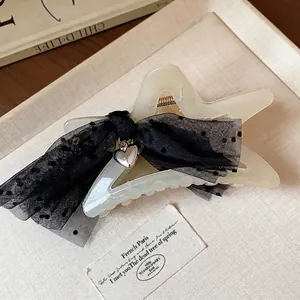 Elegant star-shaped hair claw clip with black mesh polka-dot bow and silver heart charm