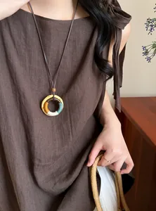 Detailed view of bohemian ethnic style wooden fruit pendant necklace on linen dress