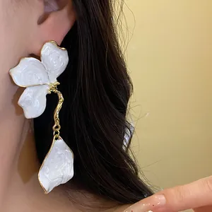Close-up of vintage white enamel flower drop earrings with gold-tone metal details