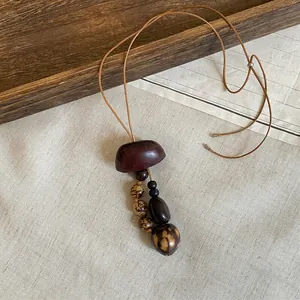 Detail view of ethnic style necklace featuring natural wooden beads and seeds.