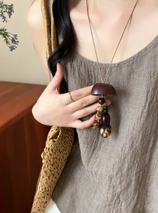 Close-up detail of a handmade ethnic style long necklace with natural wooden beads on a model.
