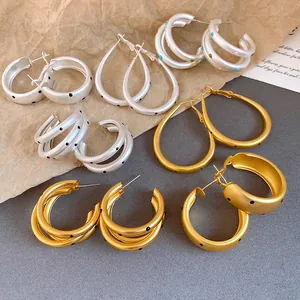 Detail view of matte silver and gold hoop earrings with black and colorful polka dots.