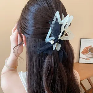 Back view detail of a large black polka dot tulle bow hair claw clip on long hair