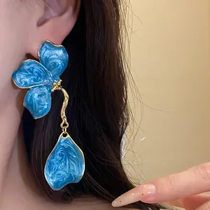 Close-up of vintage blue enamel flower drop earrings with elegant golden trim finish