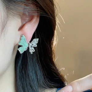 Élégante boucle d'oreille papillon en argent avec verre vert et zircons brillants sur l'oreille.