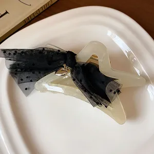 Close-up of star-shaped hair claw clip with black polka dot mesh bow detail
