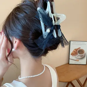 Elegant star-shaped hair claw clip with black polka dot mesh and pearl accents worn by a model.