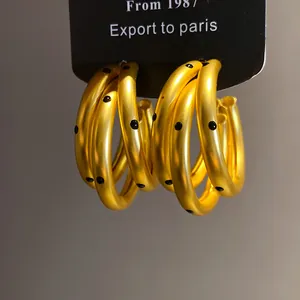 Close-up of golden hoop earrings featuring a stylish black polka dot pattern design