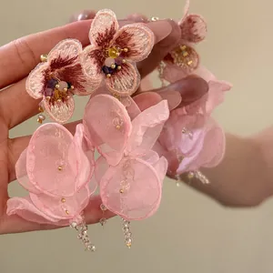 Primer plano de delicados pendientes de borla de flores de gasa rosa con bordados finos