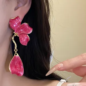 Close-up of retro pink flower enamel dangle earring worn on model for detail.