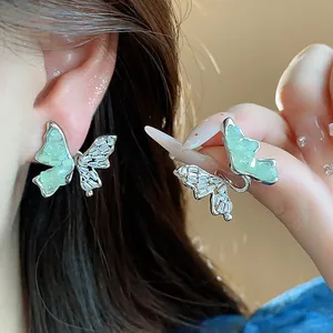 Détail de boucles d'oreilles papillon en argent avec zircons et verre vert texturé
