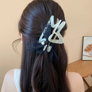 Detail view of a large mesh polka dot bow hair claw clip styled on long wavy brown hair