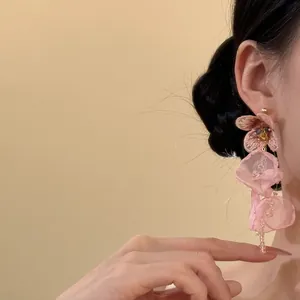 Detalle de elegantes pendientes de borla con flores de gasa rosa usados en modelo para un look