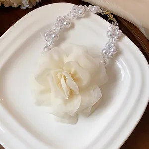 Detailed view of an elegant off-white chiffon flower and pearl bead necklace on a white plate