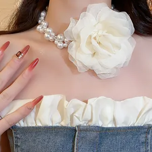 Close-up of white chiffon flower pearl choker necklace on elegant model's neck.