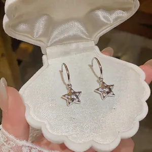 Primo piano di orecchini a stella in zircone in una scatola per gioielli a forma di conchiglia