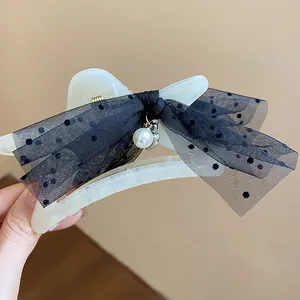 Detail view of cream star hair claw clip with black polka dot mesh bow and pearl