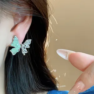 Détail d'une boucle d'oreille papillon avec verre vert et zircons scintillants