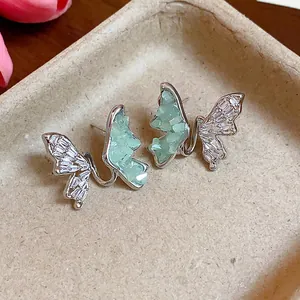 Gros plan de boucles d'oreilles papillon avec pierres vertes et zircons