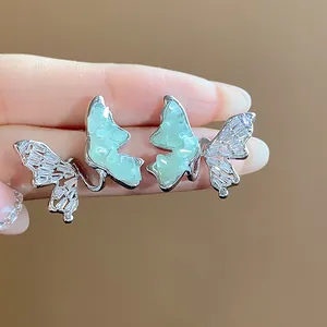 Détail de boucles d'oreilles papillon en argent avec zircon et pierres de verre vertes