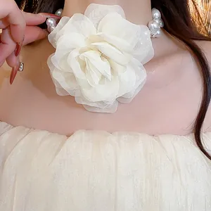 Detailed close-up showing the delicate cream chiffon flower and pearl beads on a necklace