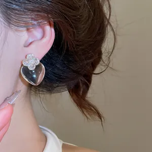 Gros plan élégant d'une boucle d'oreille transparente en forme de cœur avec trèfle