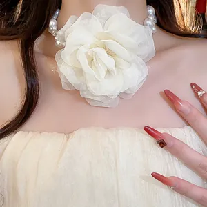 Close-up detail of elegant white chiffon flower choker with pearl and glass beads on model