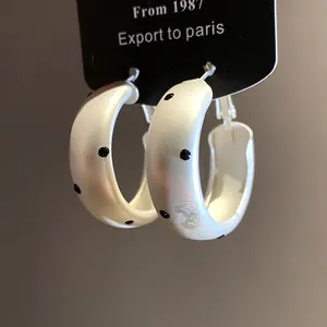 Detailed macro view of matte silver hoop earrings featuring black polka dot patterns