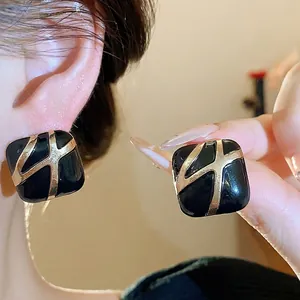 Vintage black enamel square stud earrings with golden cross pattern and silver needle