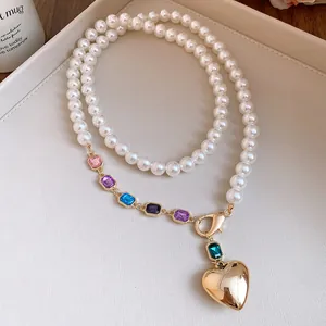Detailaufnahme einer Perlenkette mit bunten Strasssteinen und goldenem Herzanhänger