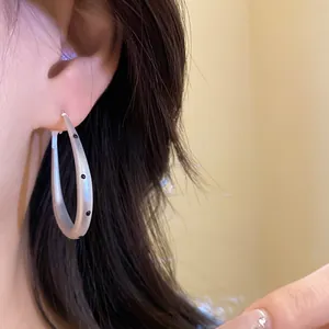 Detail view of silver oval hoop earrings with black polka dot patterns on model ear