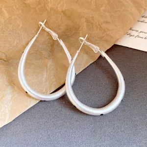 Detailed view of matte silver teardrop hoop earrings with black polka dots