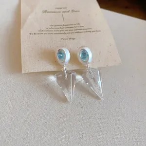 Vue macro d'élégantes boucles d'oreilles cônes avec pierre centrale bleue.