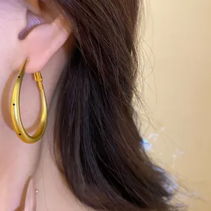 Close-up of minimalist matte gold oval hoop earrings with stylish black polka dots