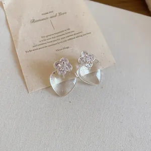 Vue détaillée de boucles d'oreilles élégantes en forme de cœur transparent avec trèfle