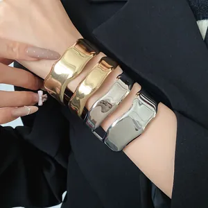 Close-up view of stylish gold and silver irregular smooth open bracelets on a model's wrist