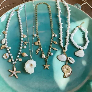 Detailed macro view of ocean-themed necklaces with shell and starfish charms on a teal plate