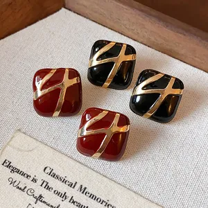 Macro detail of vintage square enamel earrings in red and black with gold accents