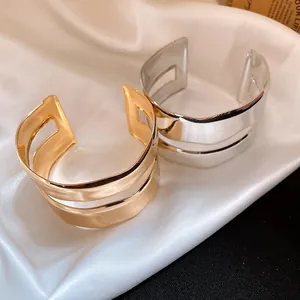 Macro detail of high-quality smooth gold and silver double-layered open cuff bracelets.