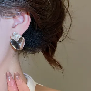 Gros plan de boucles d'oreilles cœur transparentes élégantes avec design de trèfle cristal.