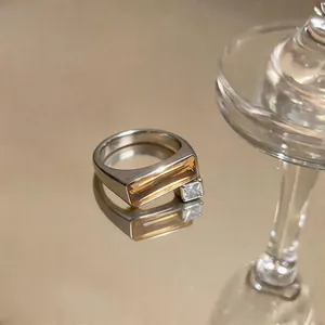Close-up of geometric ring with amber rectangular stone and clear square diamond inset