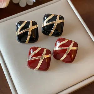Detailed macro view of vintage square enamel stud earrings with golden abstract pattern