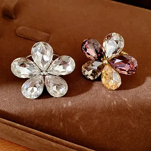 Close-up of two oversized flower rings with sparkling teardrop crystals on velvet tray