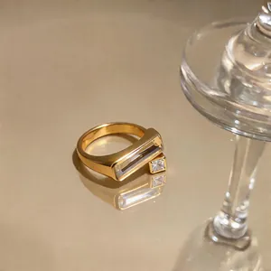 Macro view of a gold geometric ring with clear stones on a reflective surface.