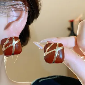 Close-up of vintage square drop oil earrings with gold-tone abstract design