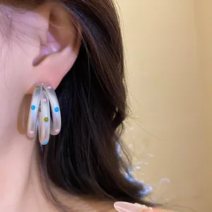 Detailed view of frosted multi-layered silver hoop earrings with vibrant polka dots