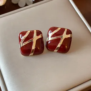 Close-up of vintage red enamel square stud earrings with gold cross pattern