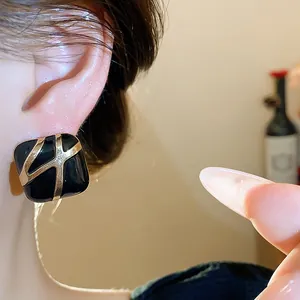 Close-up detail of retro black enamel square stud earrings with gold geometric lines